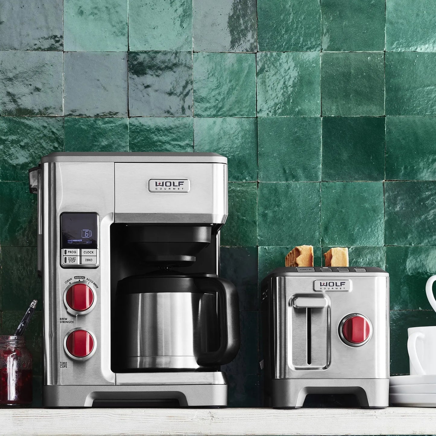 Wolf Gourmet automatic drip coffee maker with a 10-cup glass carafe and digital control panel on a kitchen countertop.